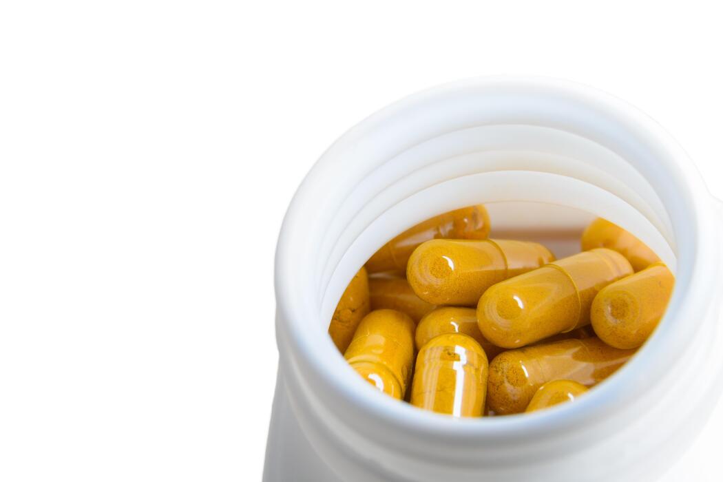 What is the strongest natural pain reliever - turmeric herb capsule, close up image in white background.
