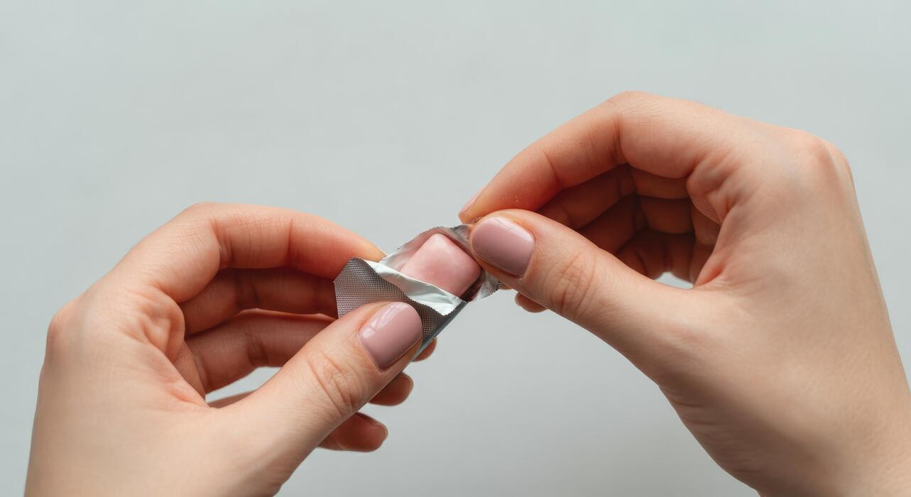 Sildenafil oral jelly how to use - Close-up of hands unwrapping piece pink chewing gum
