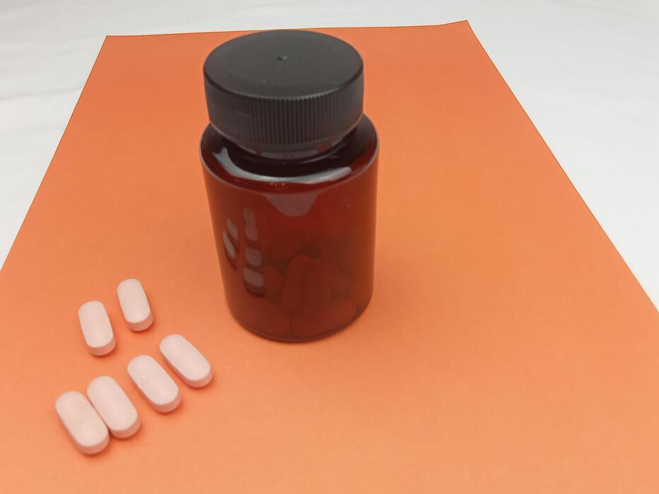 Sildenafil oral jelly how to use - Medicine bottle and white pills on orange background with copy space