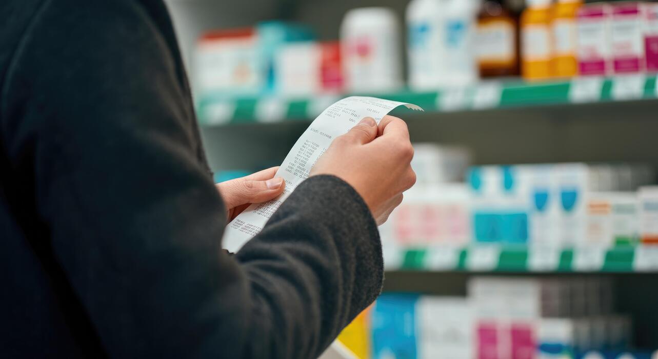 Viagra pills price - Person holding prescription in pharmacy surrounded by medication shelves