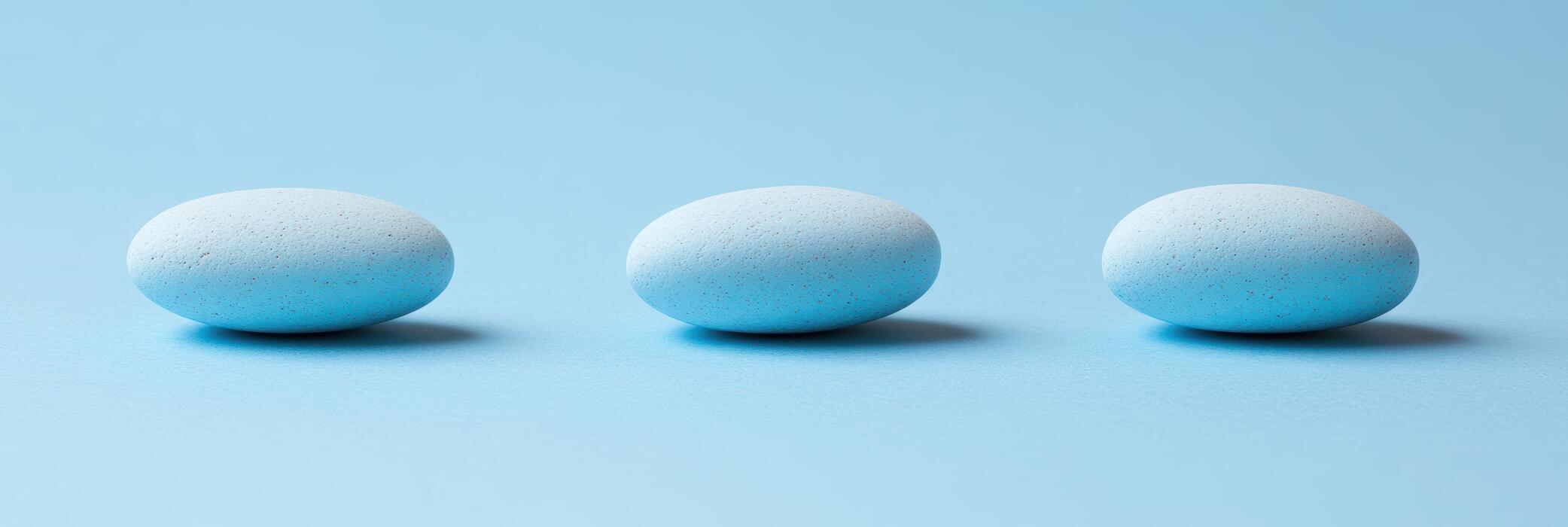 Viagra Connect - Blue oval stones arranged in a straight line on a light blue background