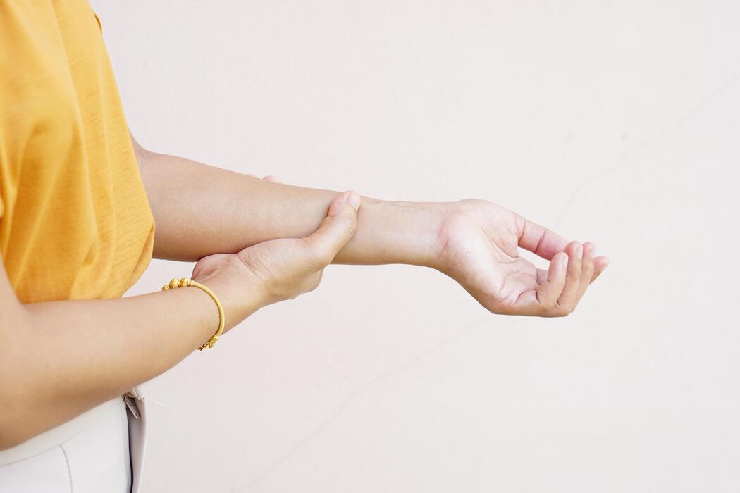 how to fall asleep faster with insomnia - Woman holding her wrist pain from using computer, office syndrome