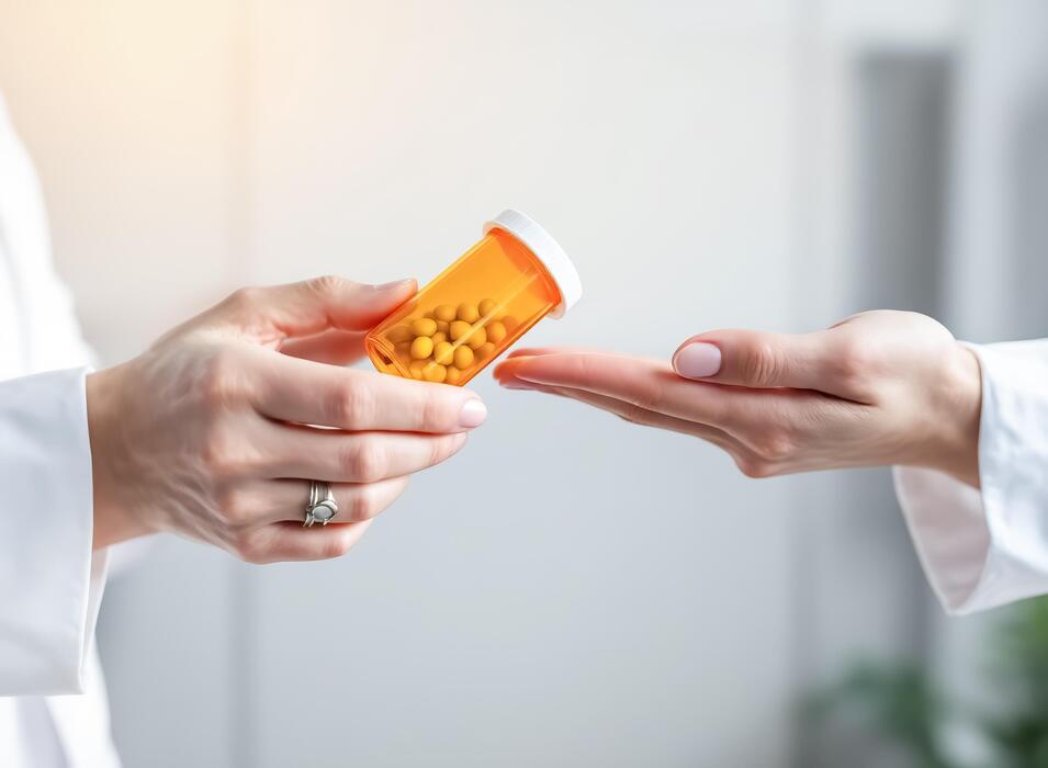What are the top five sleeping pills? - A healthcare professional provides a medicinal amber vial to a patient. This prescription container and pill canister contain small yellow capsules for daily treatment.