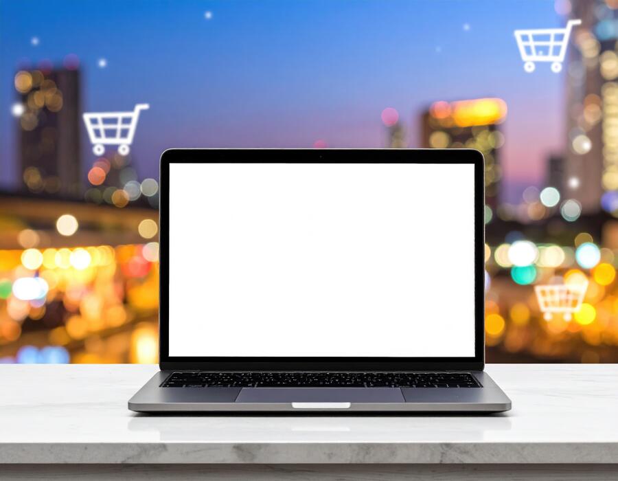 ecommerce basics for small businesses uk - Laptop with shopping cart on the table with cityscape background
