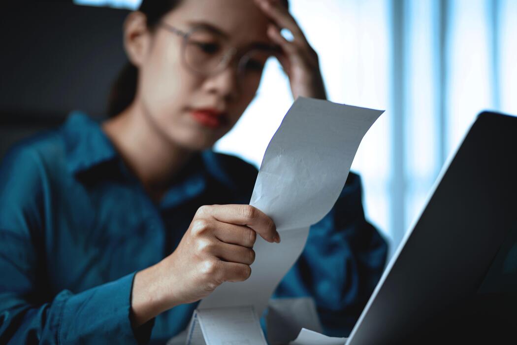 ecommerce basics for small businesses uk - A woman is holding a piece of paper and looking at it with a sad expression