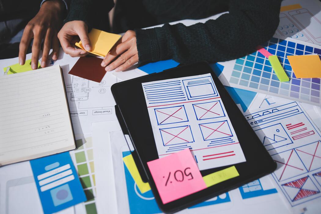 Cheapest website builder UK - A person is working on a laptop with a paper and sticky notes