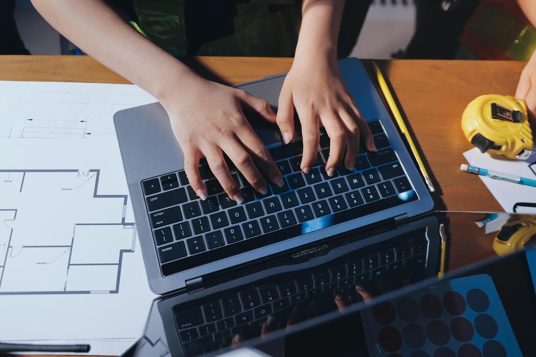 how much does a small business website cost uk - A person typing on a laptop computer with construction plans