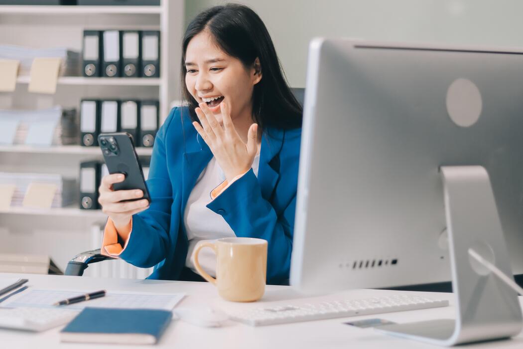 how fast should a small business website be - A woman in a business suit is holding her phone and laughing