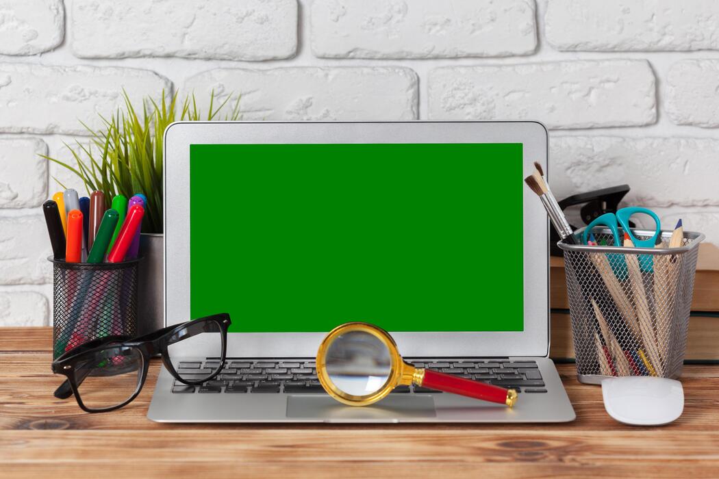 how fast should a small business website be - Laptop with green screen and office supplies on wooden table