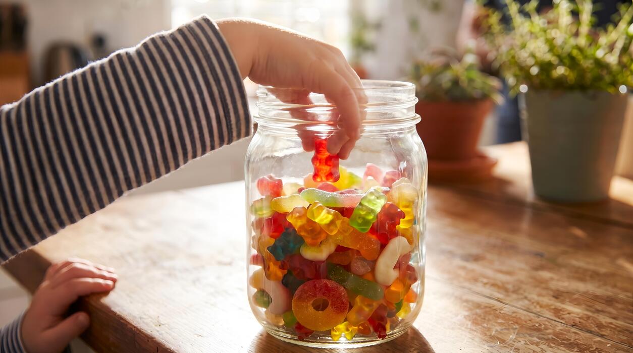 essex sweet cart hire - Gummy Candies in a Glass Jar Reached by a Child at Home Table