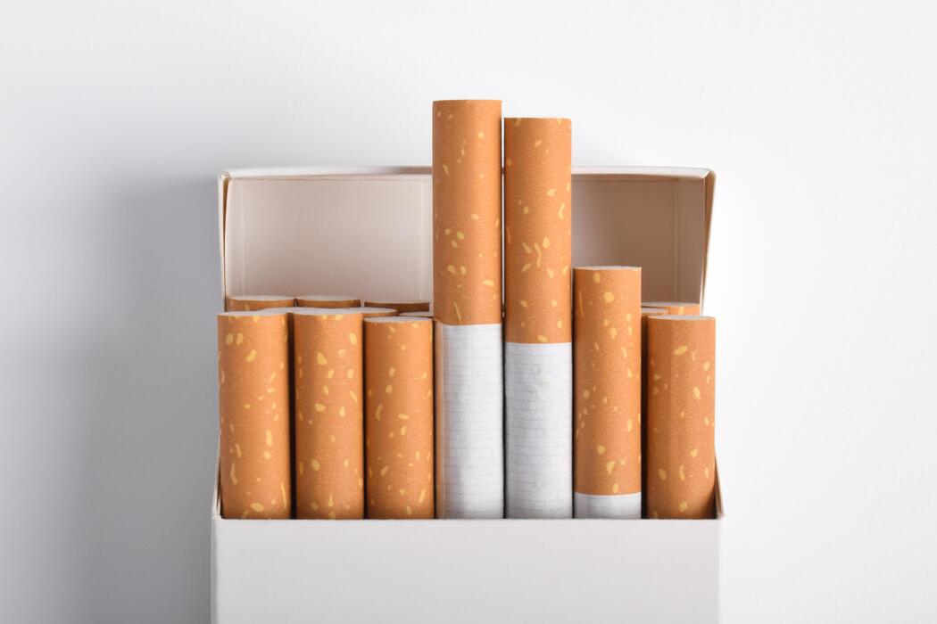 Cigarettes price - Open Pack of Cigarettes with White and Brown Filters on White Background.