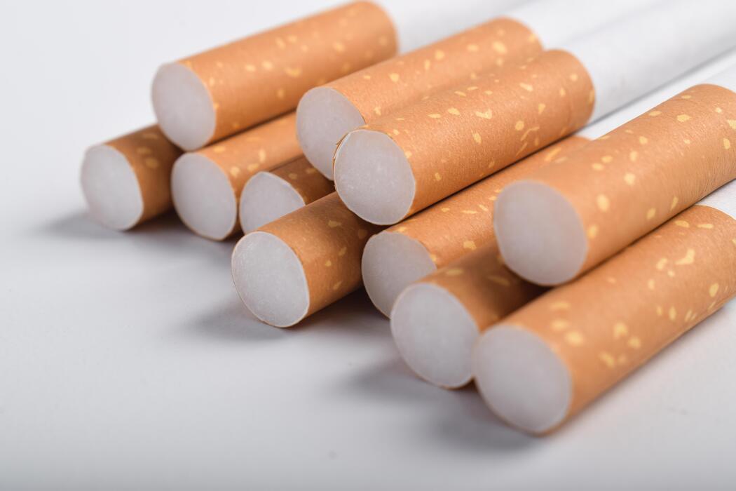 superkings cigarettes australia - Close-up of a pile of unfiltered cigarettes with white filters and brown paper wrappers on a white surface.